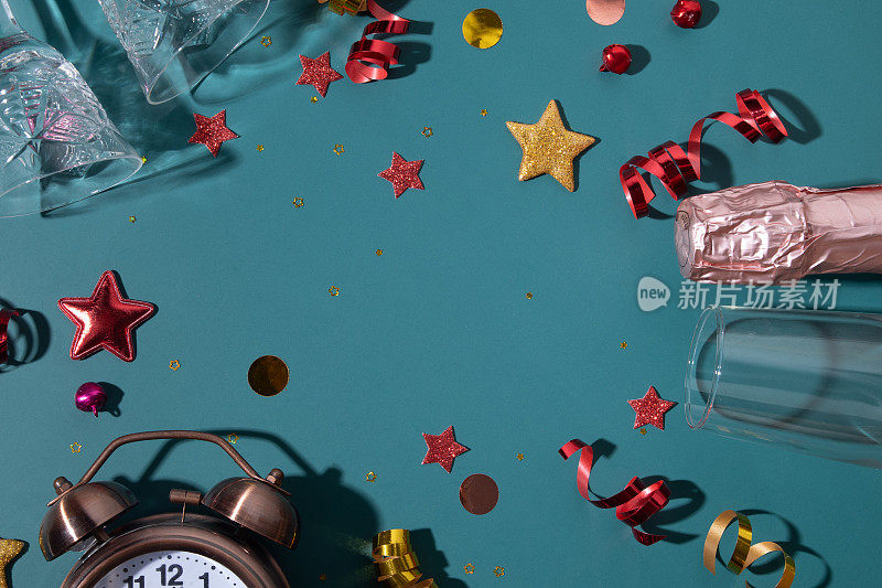 快乐的圣诞新年flat lay with champagne, glass, alarm clock and alarm clock, stars, streamers。寒假的节日背景
